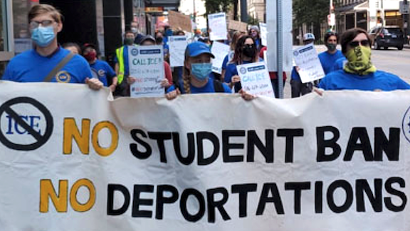 People holding a "No student ban, no deportations" sign